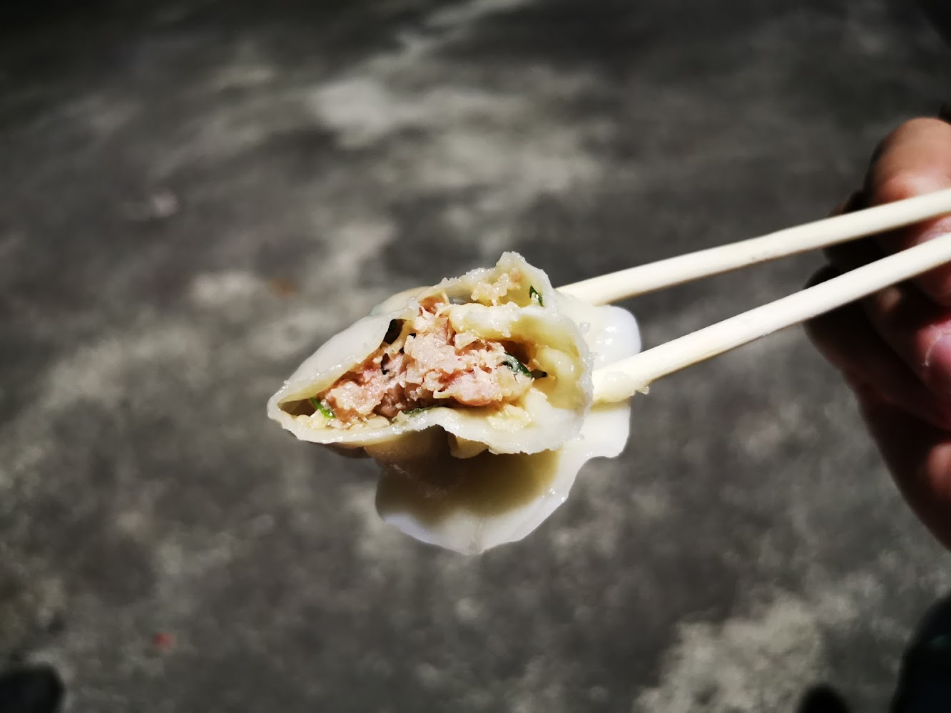 筷子夾起被咬開的水餃可見豬肉與蔬菜內餡