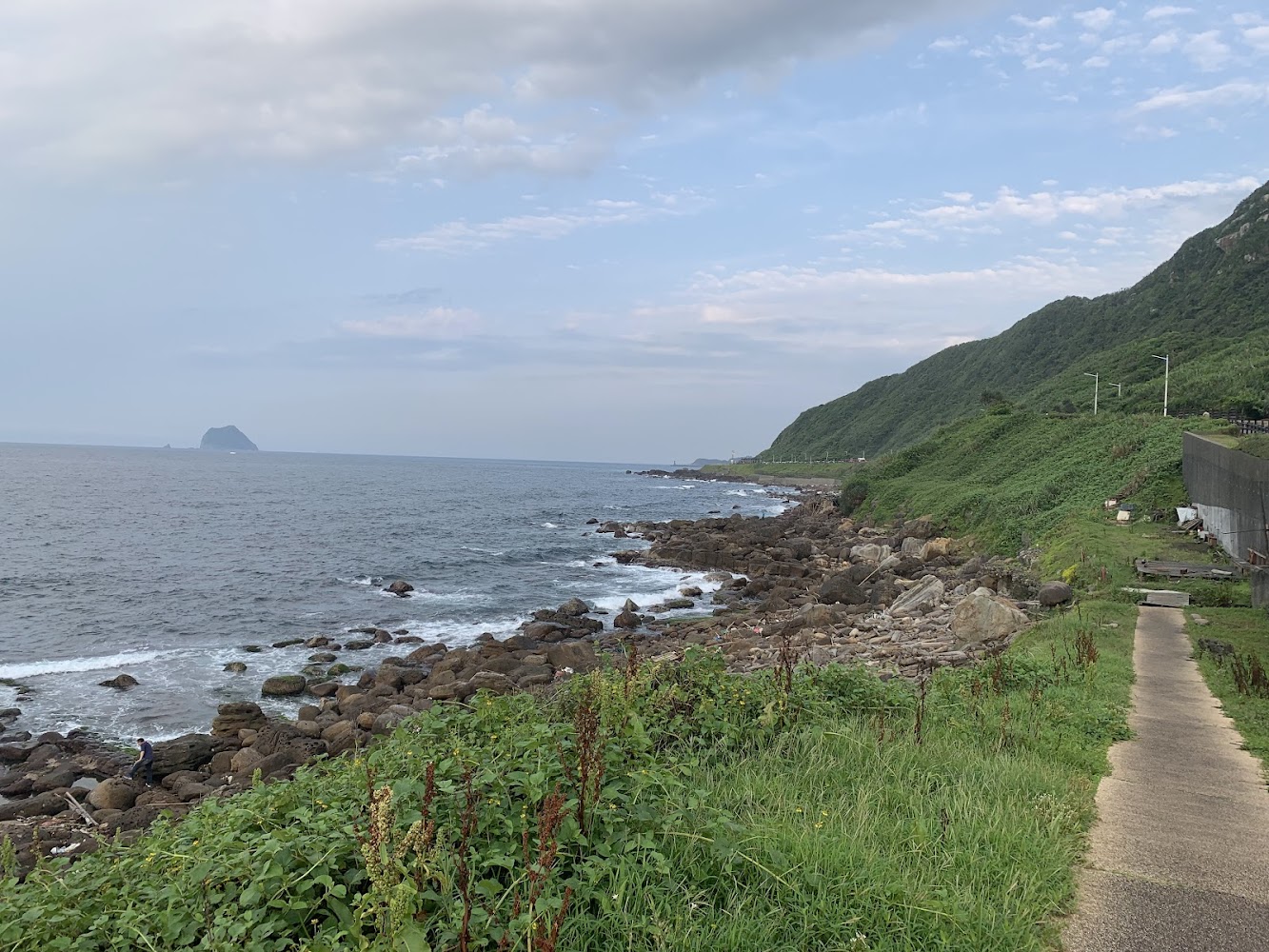 蔚藍大海與海岸步道，遠方可見山丘與小島
