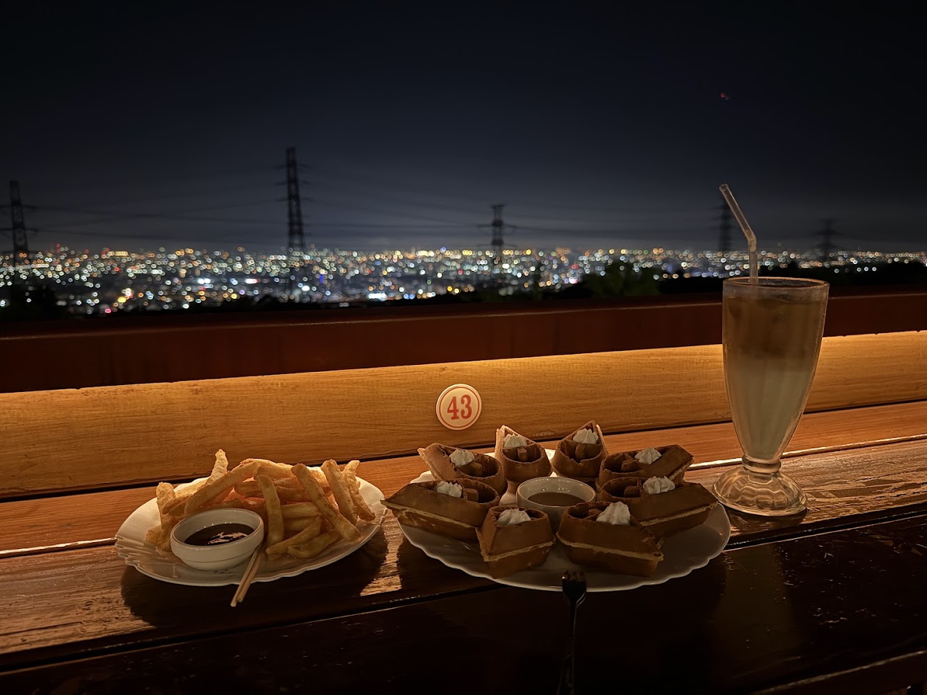 夜景搭配薯條鬆餅與飲品的餐桌