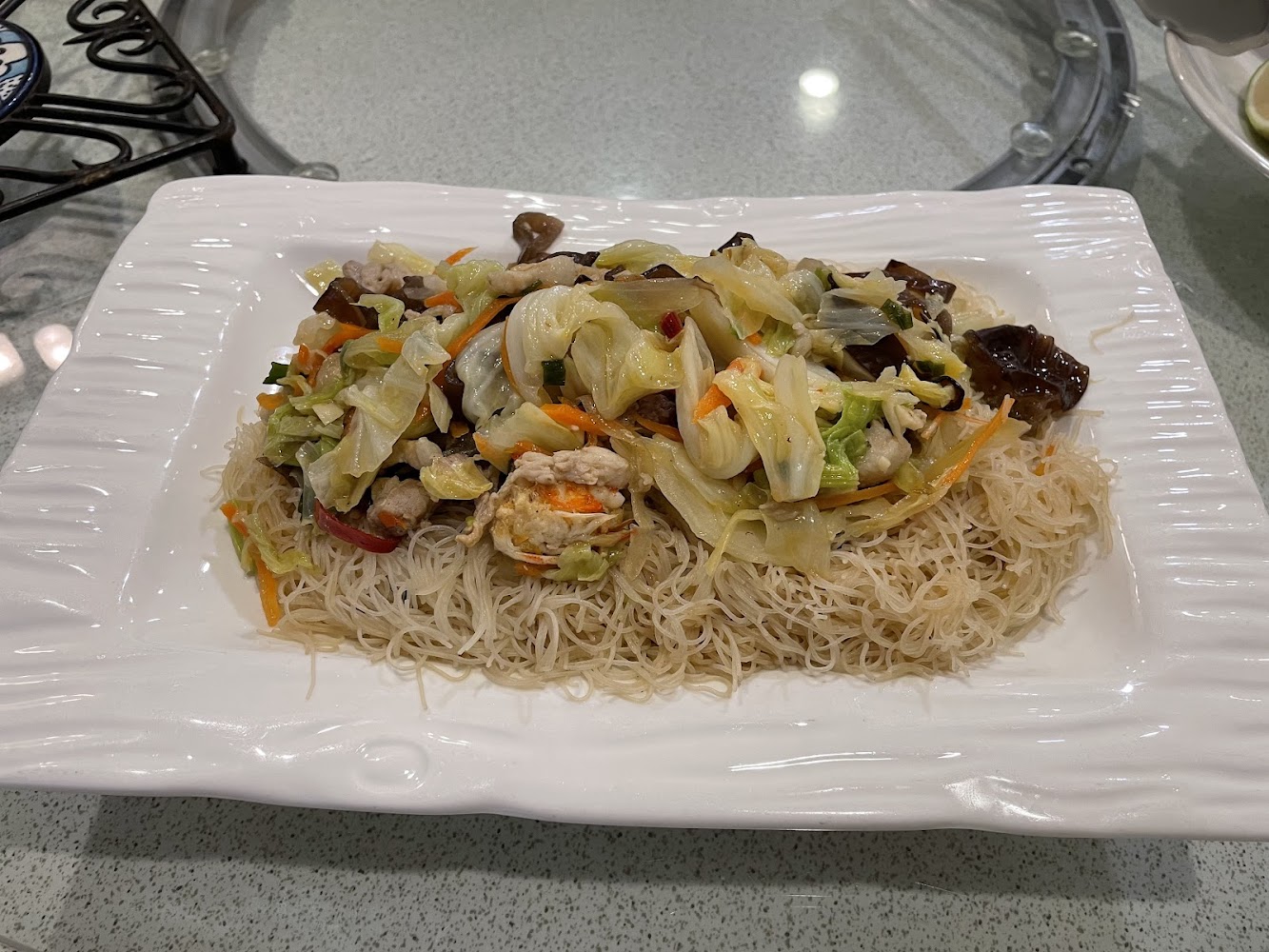 這張圖片主要是一道炒米粉，上面鋪有炒雜菜，包含高麗菜、木耳、紅蘿蔔及雞肉等配料，看起來色彩豐富，擺盤美觀。