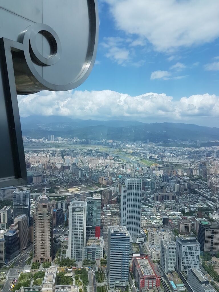 台北101觀景台俯瞰台北盆地全景，遠山藍天，台北一日遊