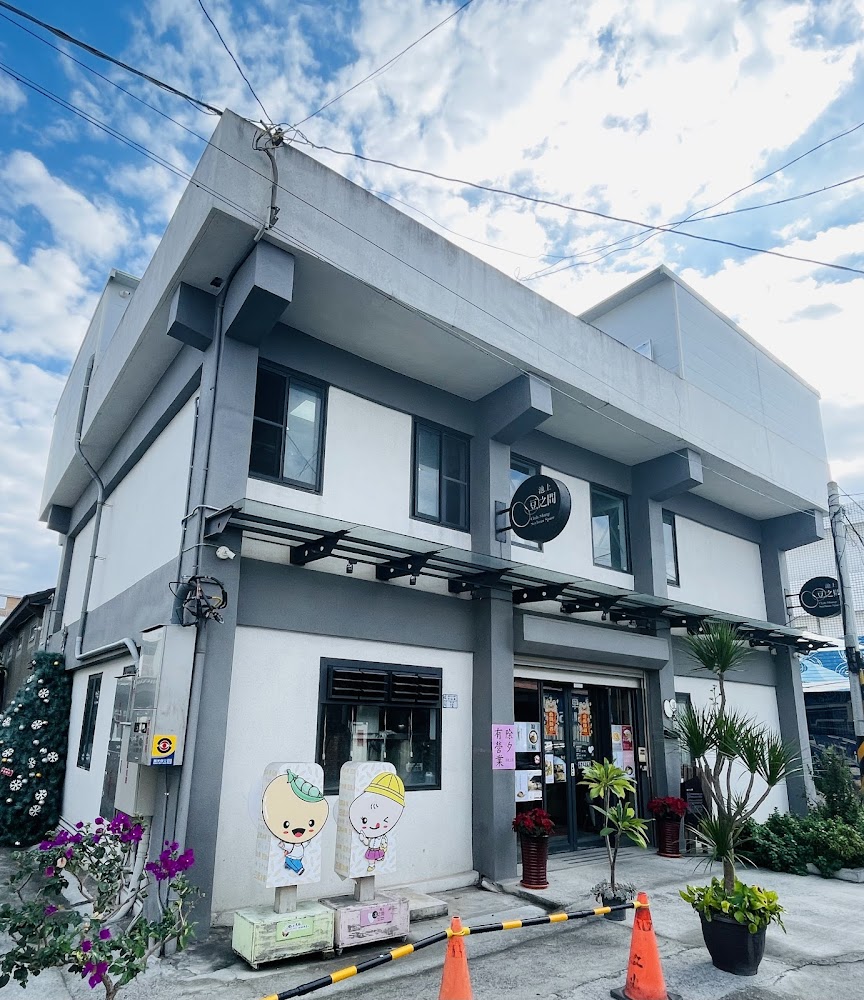 白色二層樓建築外觀，門口有可愛立牌與植栽