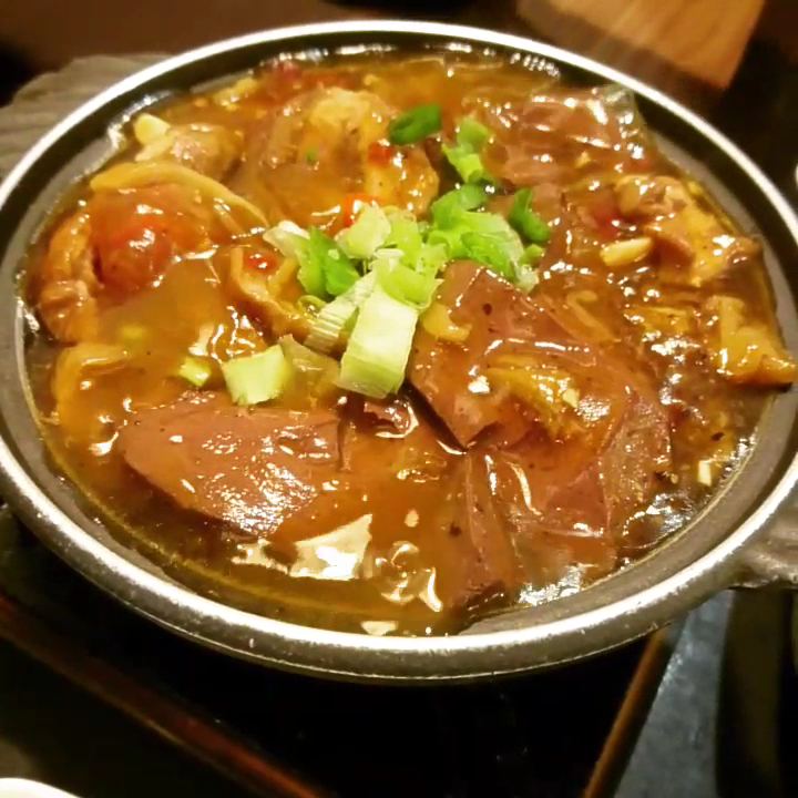 這張圖片主要是一鍋香氣四溢的麻辣鴨血豆腐煲，內有鴨血、豆腐、蔥花和辣油，湯汁濃郁，是一道受歡迎的台灣小吃。