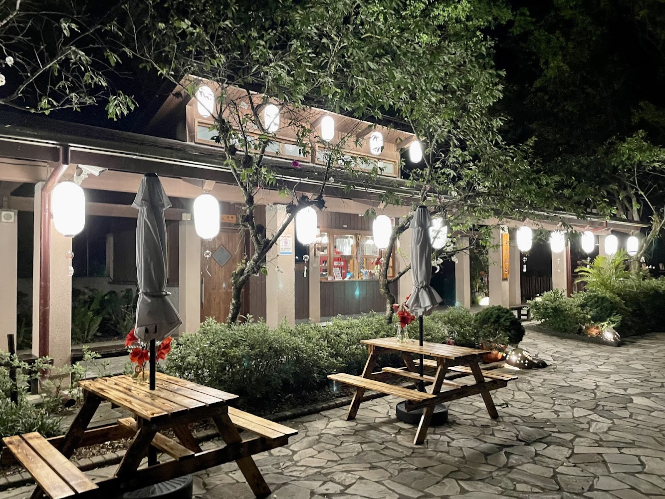 日式風格建築夜晚點燈，前方有木製座椅