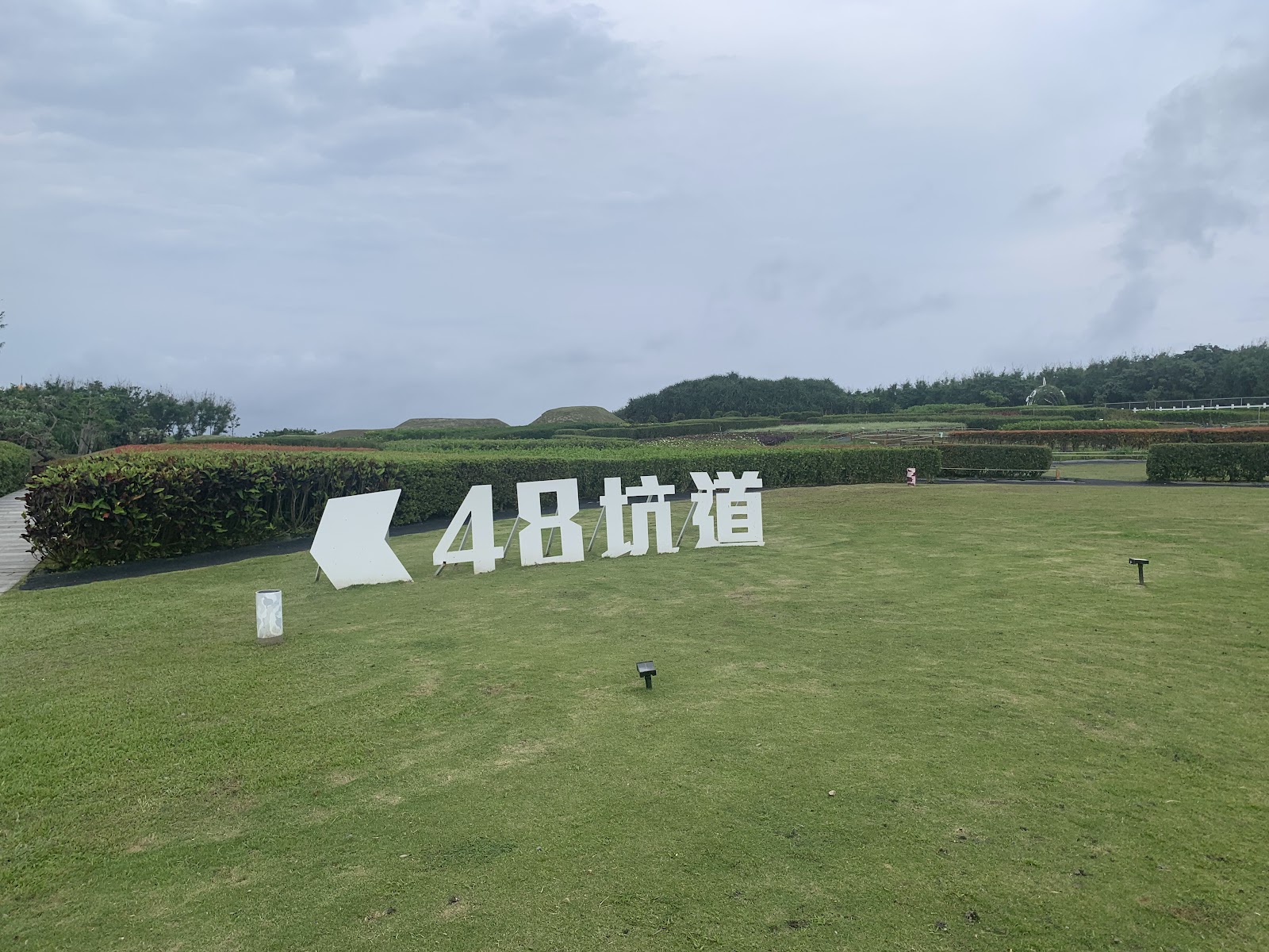 四八高地草地上的48坑道大型立體字，後方二戰軍事碉堡遺跡
