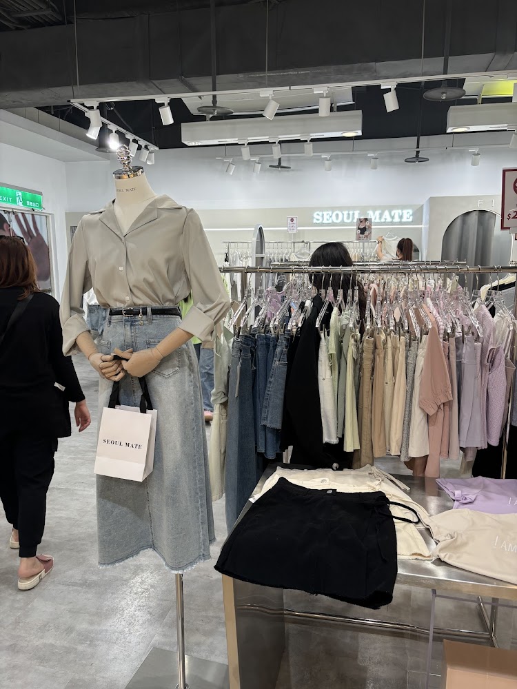 服裝店內模特兒展示襯衫與牛仔裙，旁邊陳列多樣女裝