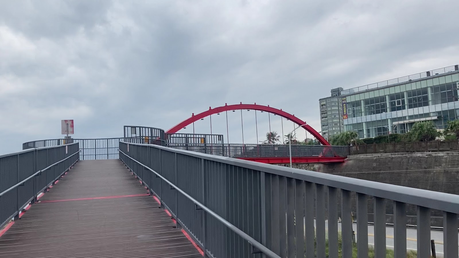 花蓮港景觀橋橋面木板步道，紅色拱形鋼橋，藍天