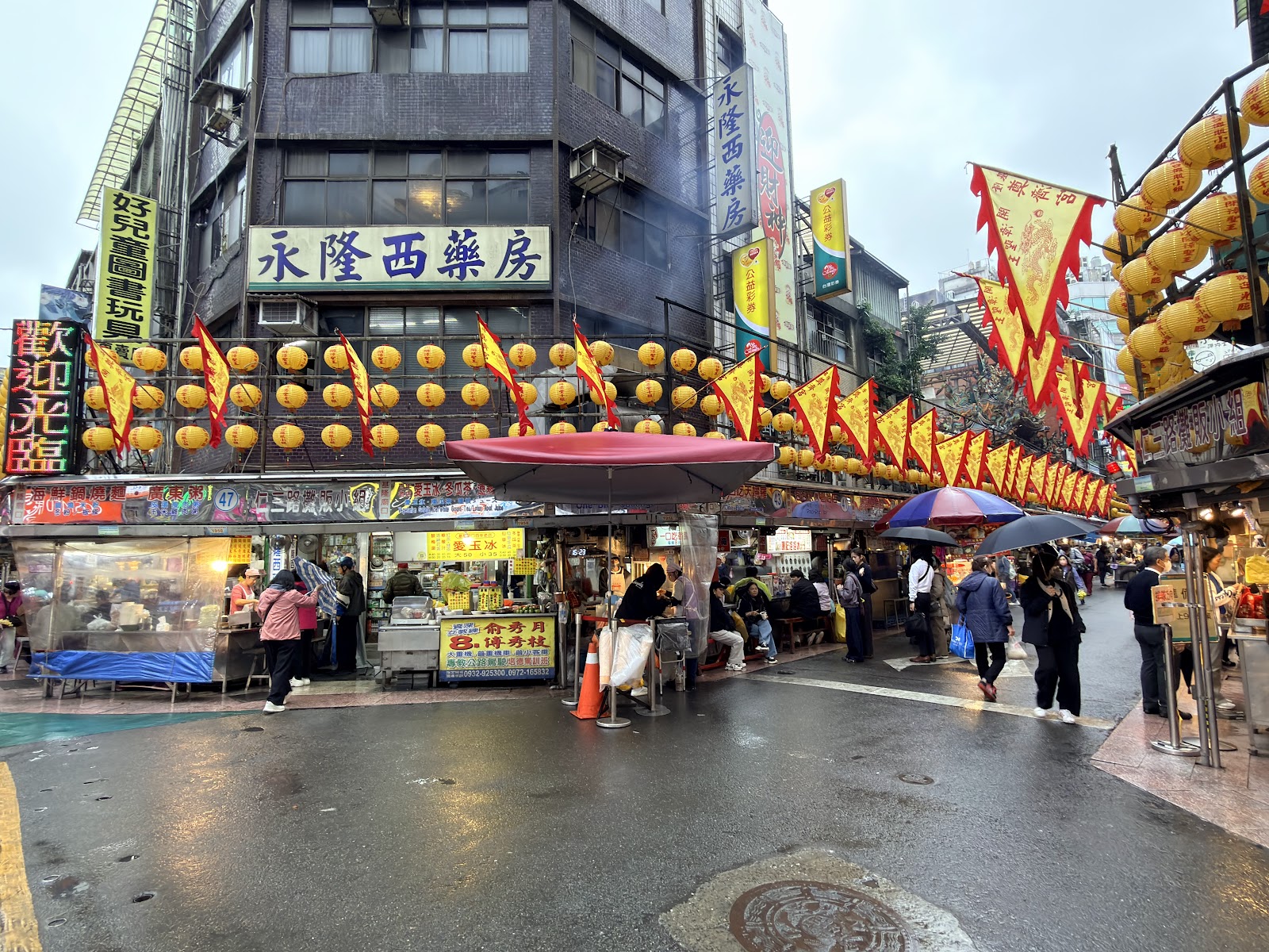 基隆廟口夜市入口處，黃色燈籠高掛，攤販林立，人群熙攘