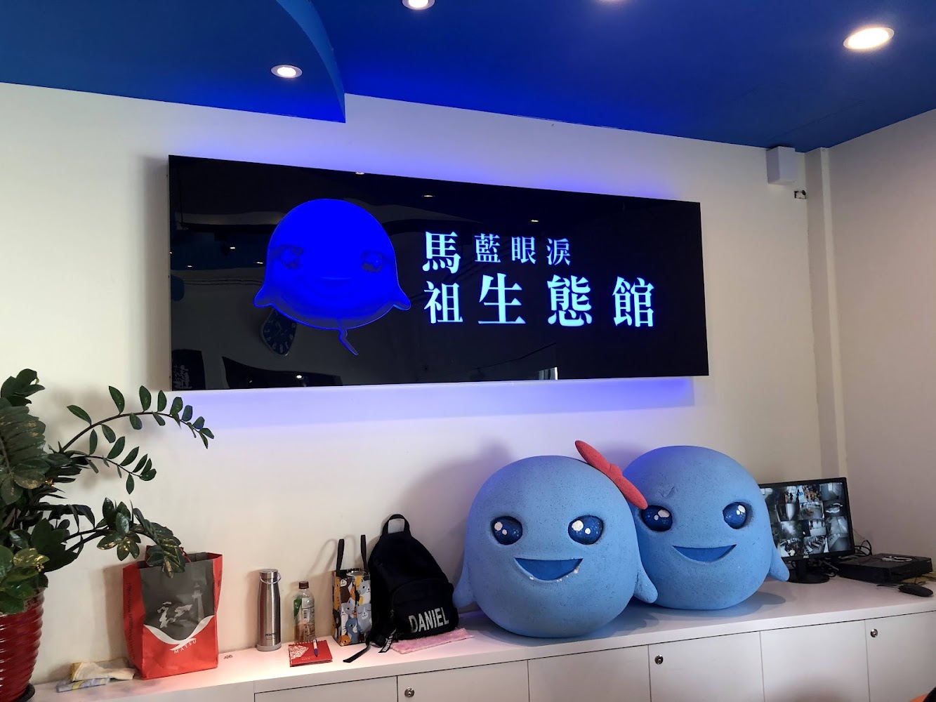 藍色吉祥物布偶與館內電視展示畫面