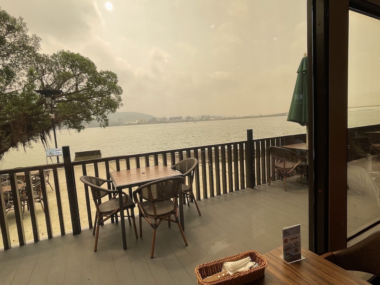 這張圖片展示了河邊咖啡廳的戶外座位區，桌椅整齊排列，可以欣賞河景與遠方城市景色，環境悠閒舒適。