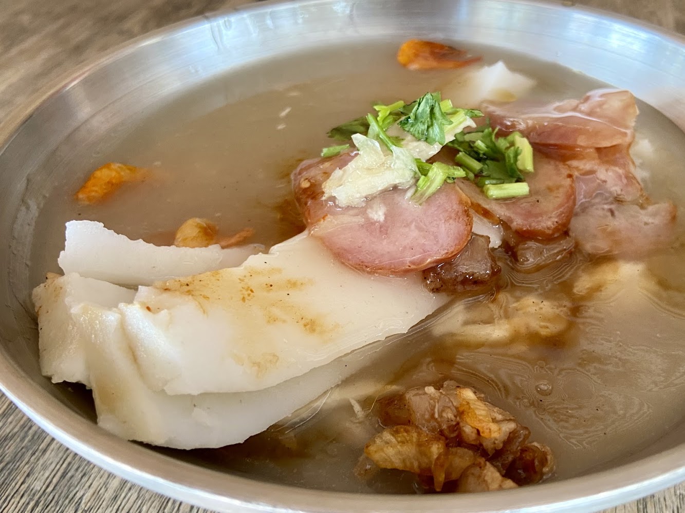 一碗米苔目鹹湯內有白色米苔目條、香腸、肉片與香菜