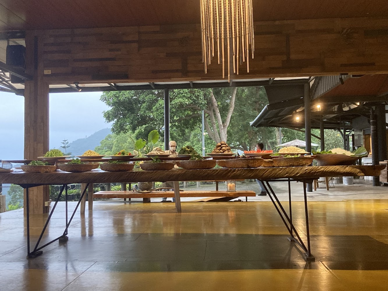長桌擺滿各式蔬菜食材背景是戶外山景與樹林