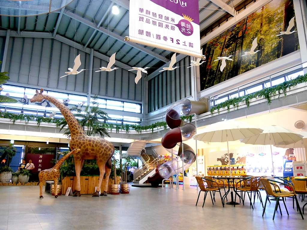 親子遊樂區有長頸鹿雕像與旋轉溜滑梯，環境明亮。