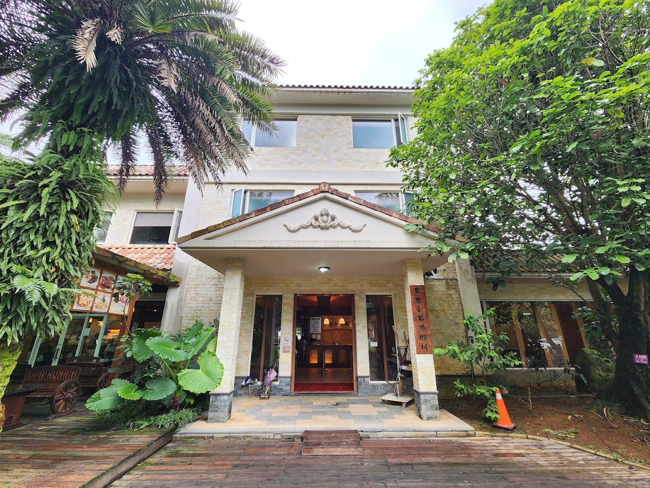 三層樓建築外觀被綠意包圍,入口明顯
