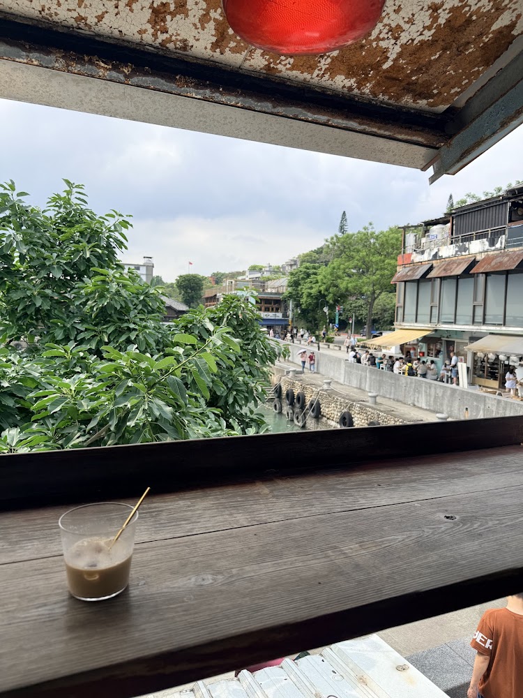 窗檯冰飲與窗外綠葉運河景觀