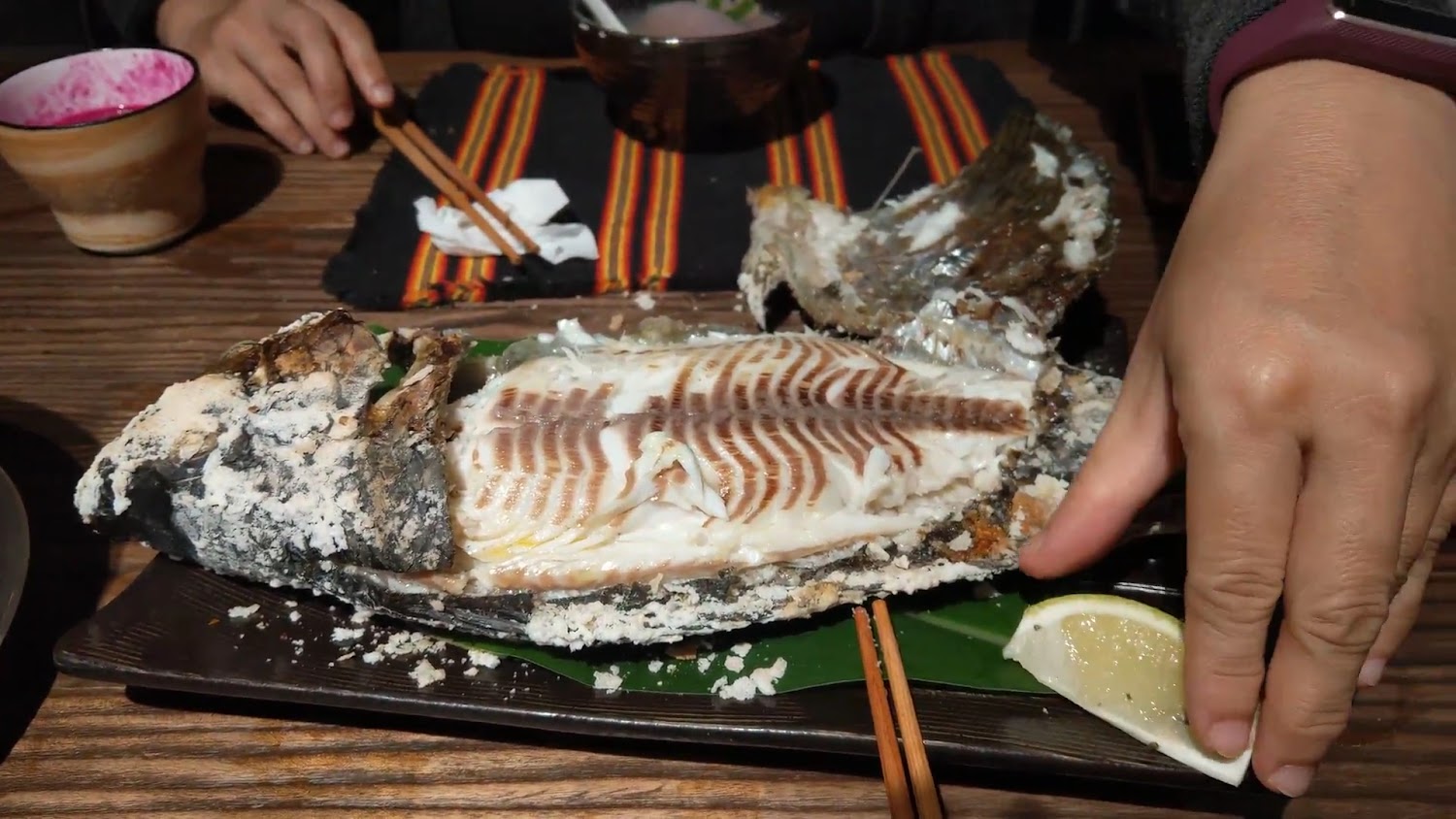 剖開後露出白嫩魚肉的鹽烤魚旁有檸檬片與筷子