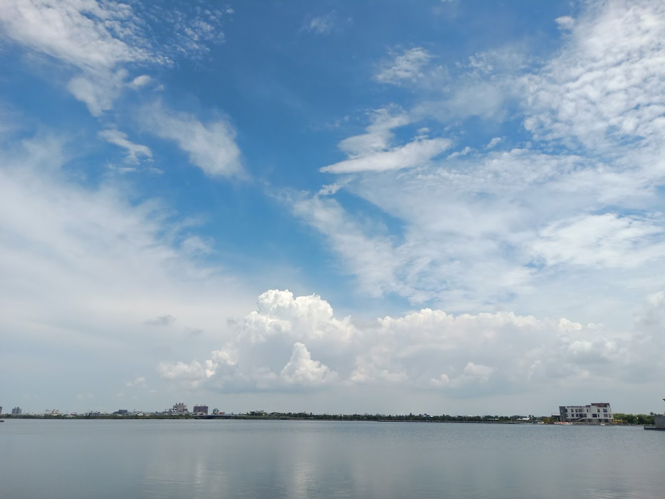 廣闊湖面遠方有建築藍天與各種形狀白雲