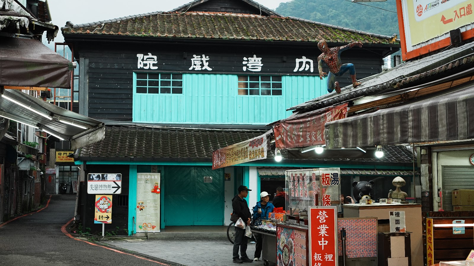 從老街角度看內灣戲院，蜘蛛人攀爬屋頂，周圍攤販熱鬧