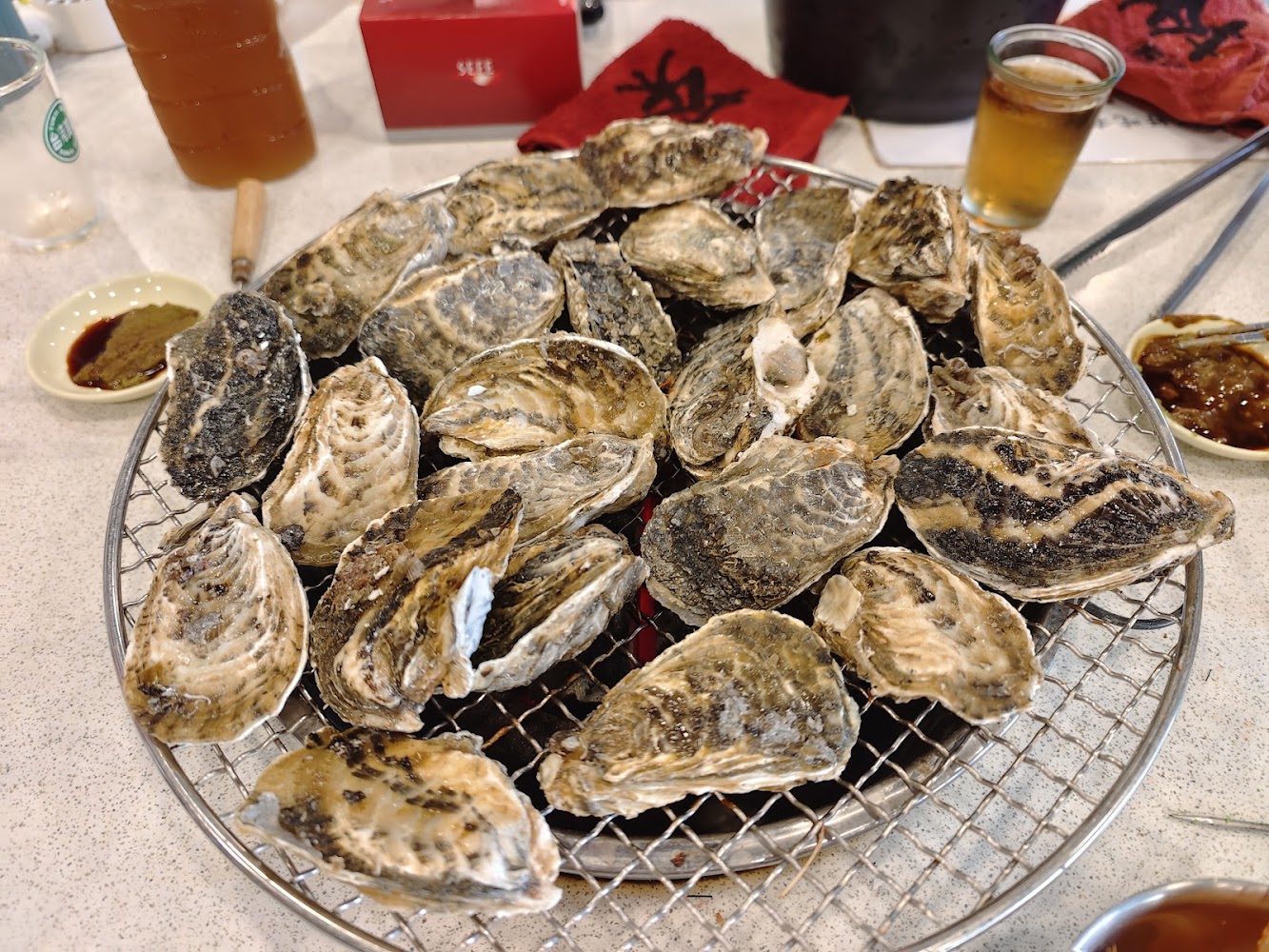 烤網上正在燒烤的生蠔與桌邊飲料
