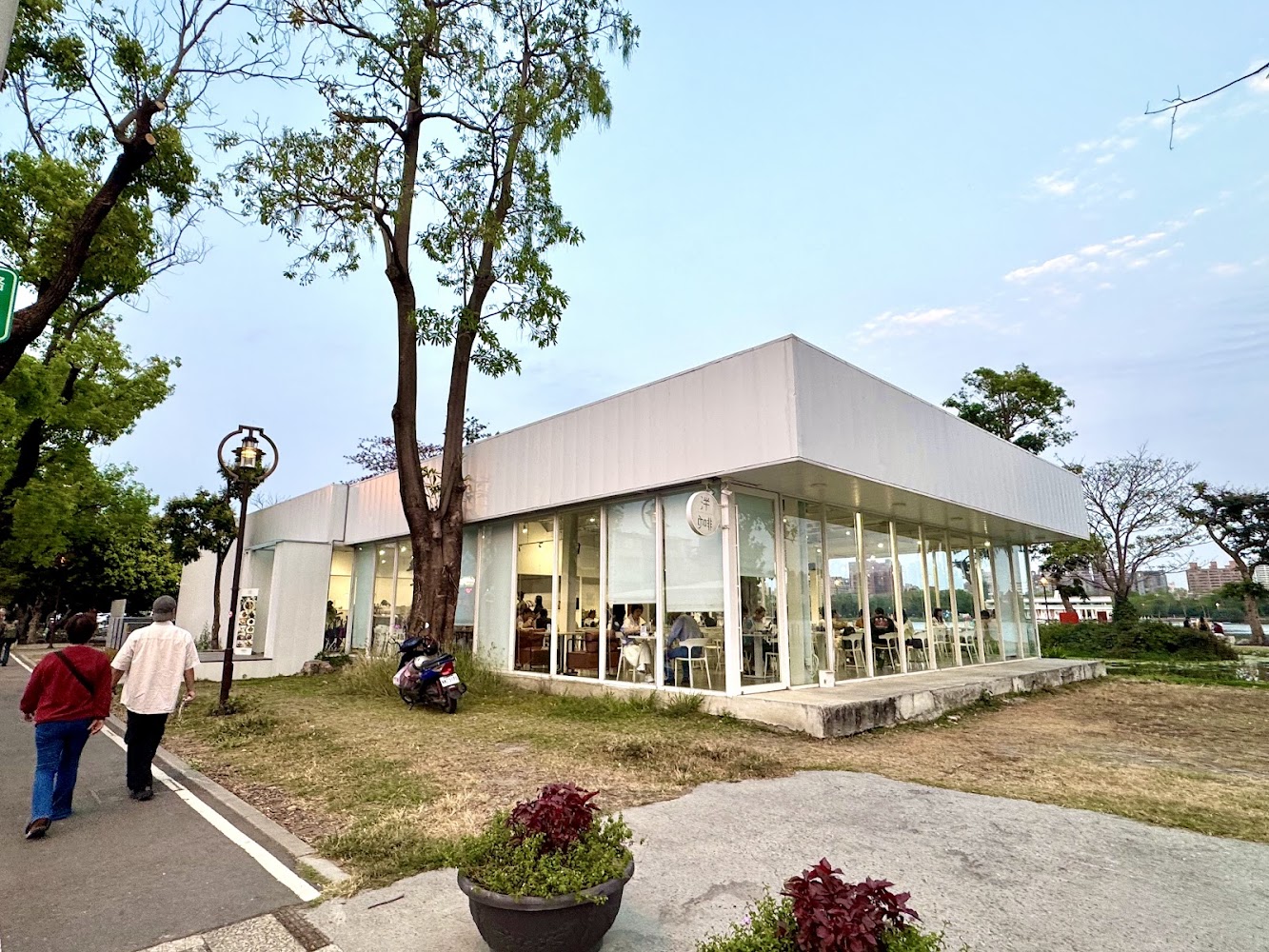 現代風格的玻璃咖啡館，四周環繞樹木和綠地