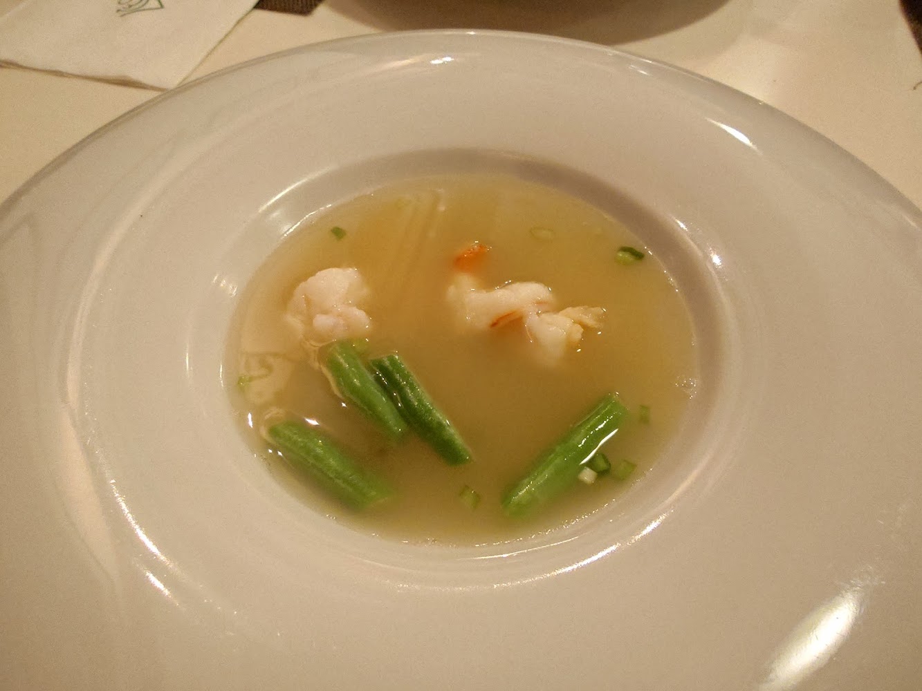 一碗清湯，湯裡有兩塊蝦仁和幾根綠色蔬菜段，擺盤簡潔