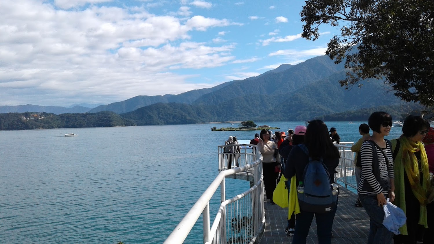 觀景平台上許多人欣賞湖景遠方山脈藍天白雲