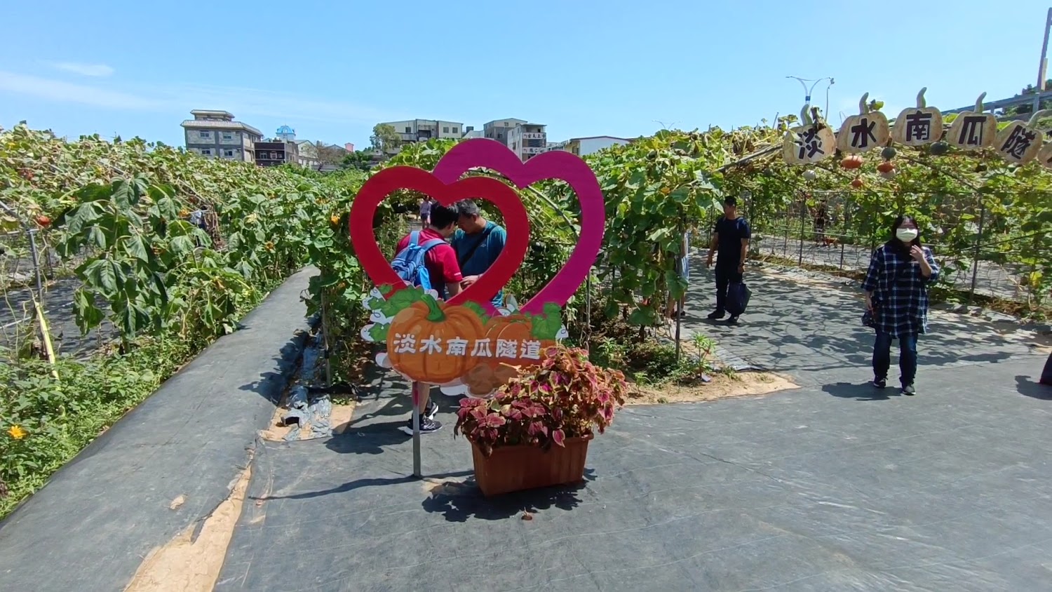 淡水南瓜隧道拱門與兩個紅色愛心裝置,現場有遊客