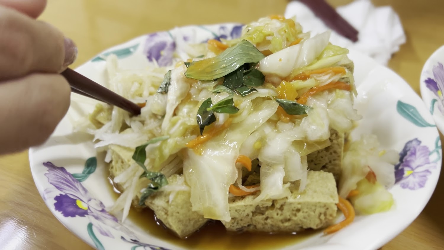 臭豆腐上鋪大量泡菜與九層塔葉，醬汁明顯