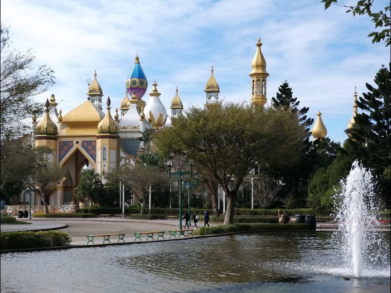 金色圓頂與尖塔的異國風格建築，前方有樹木與噴水池