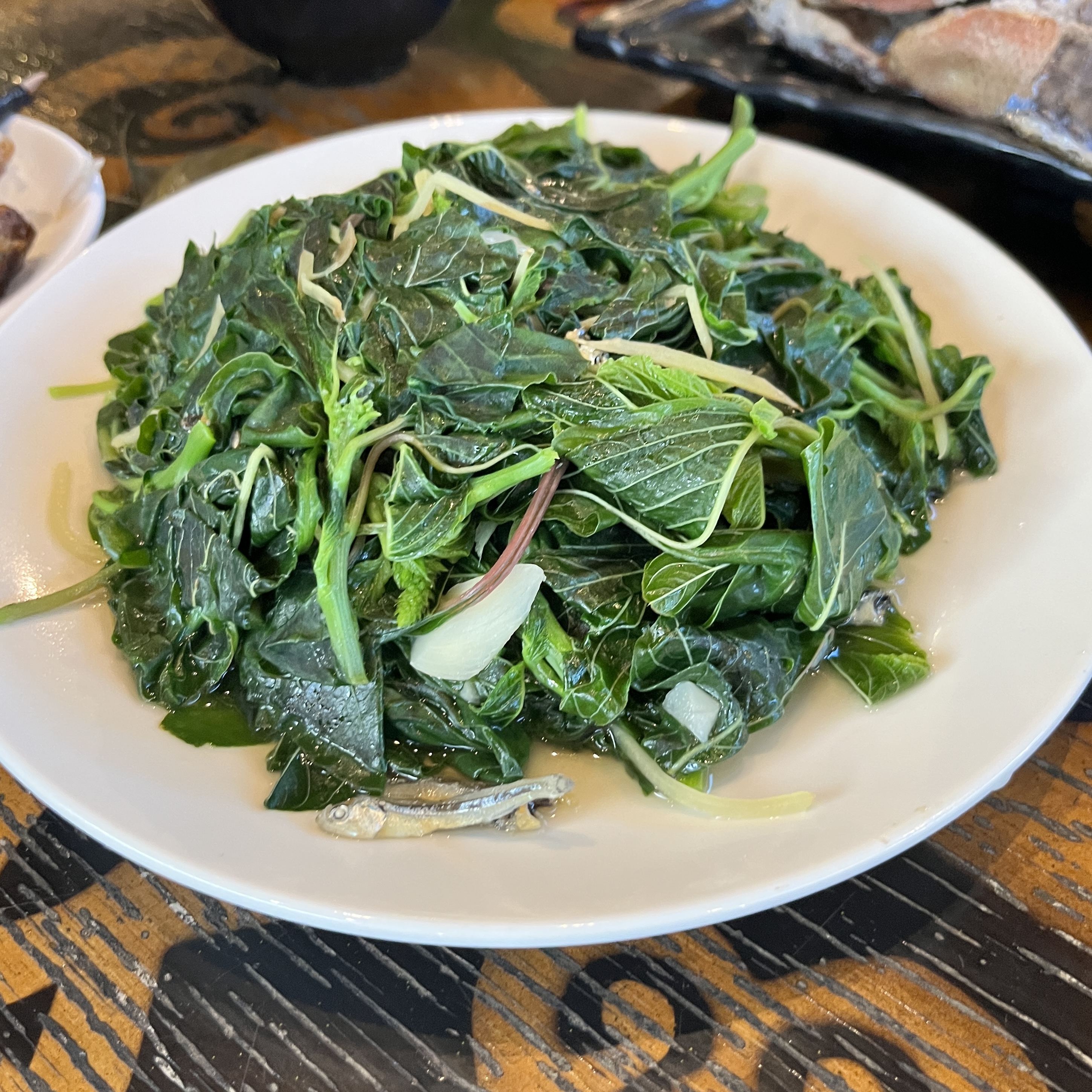 一盤炒青菜，上面有一些小魚乾，青菜鮮綠