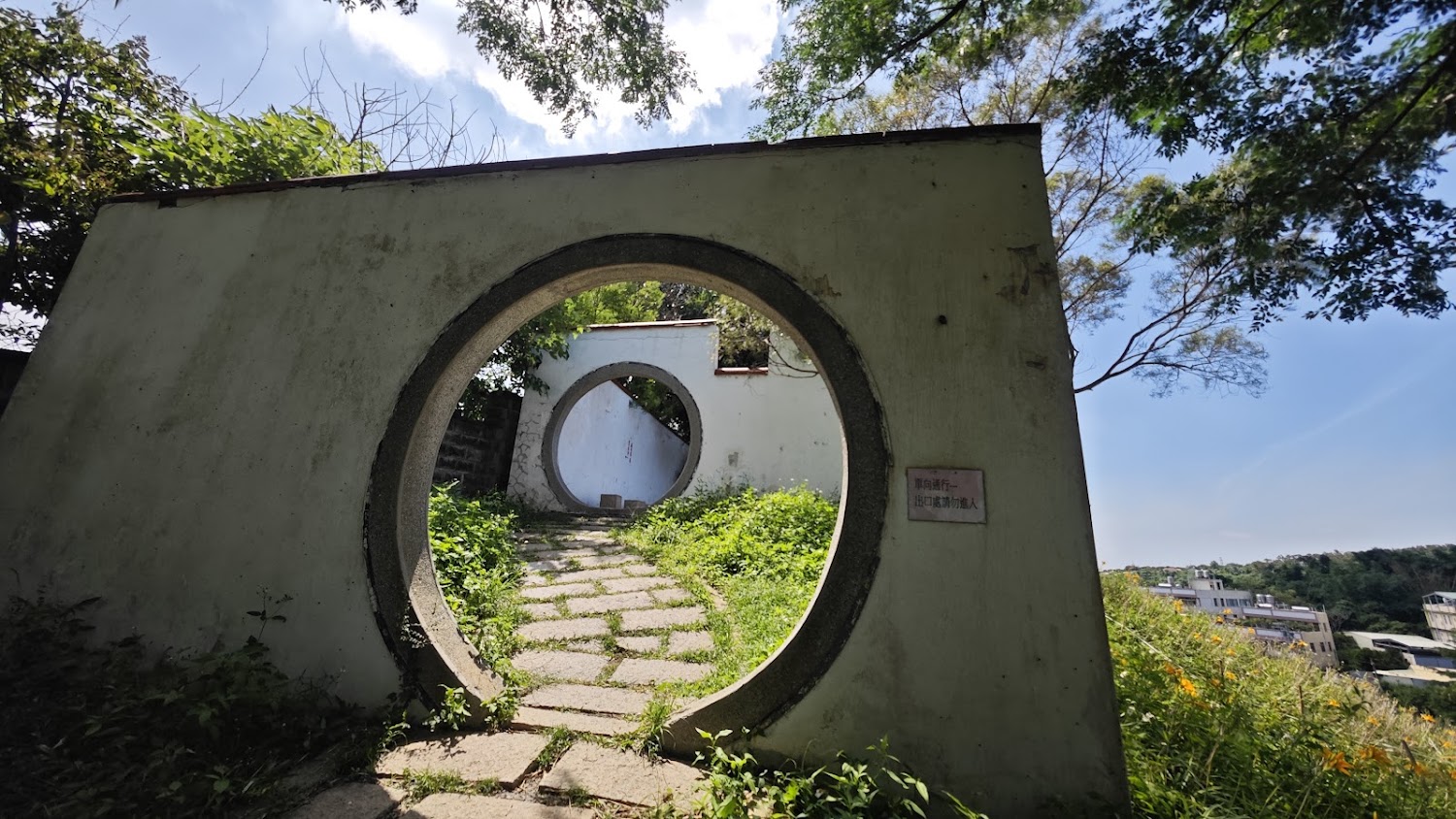 中國古風的圓形門洞與石板小徑穿過綠意花園