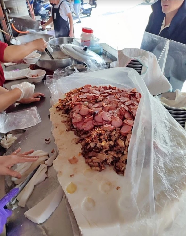 台灣傳統小吃攤上有白色粿體，覆蓋香腸與肉燥，工作人員正在切割