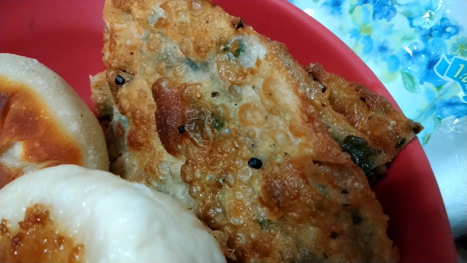 紅色盤子內的蔥油餅和兩顆煎包