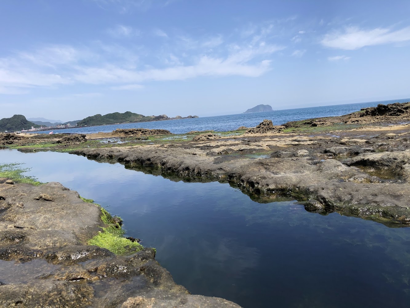 潮間帶岩石與遠方海岸山丘交織的北海岸景色
