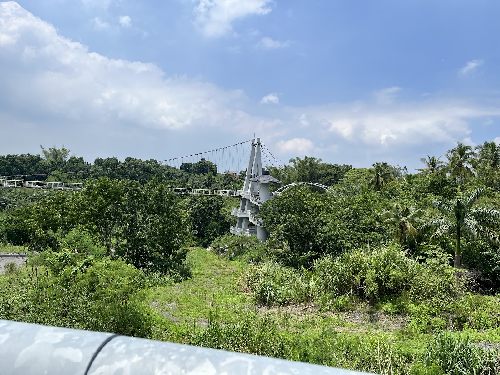 映月橋白色吊橋遠景，熱帶植被，藍天