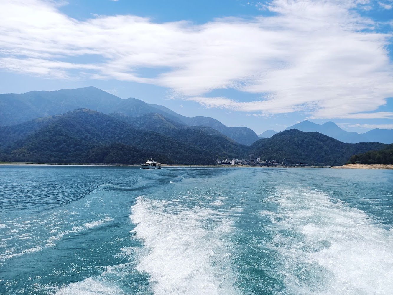 快艇在湖面航行留下水花與青山景色