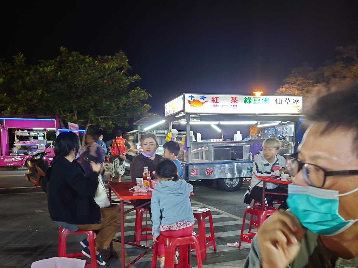 甲仙夜市夜景，民眾坐紅色椅桌享用小吃，攤位燈火通明