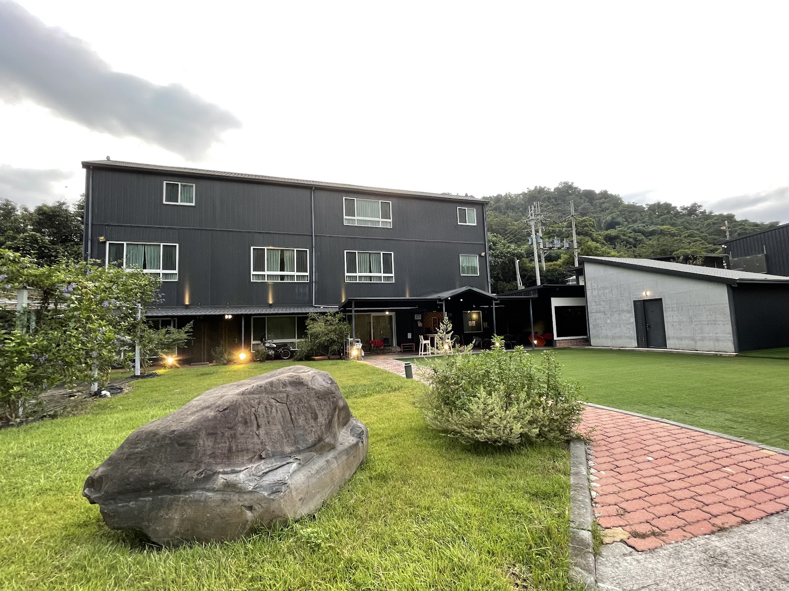 黑爵士民宿主樓正面，三層工業風黑色建築與大石頭草坪
