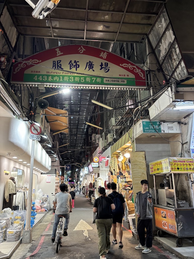 五分埔服飾廣場入口，兩旁是服飾店與逛街人潮。