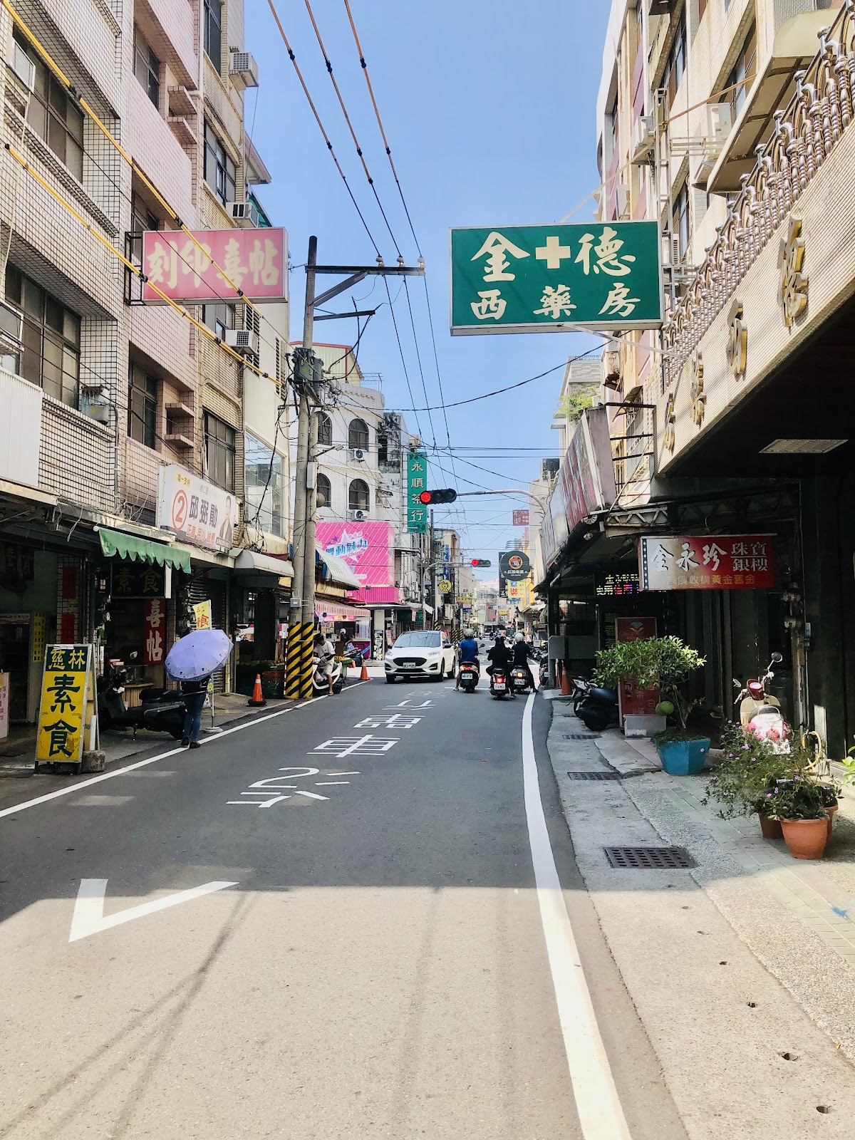 旗山老街街道，金十德西藥房綠色看板，晴天藍空老建築兩側林立