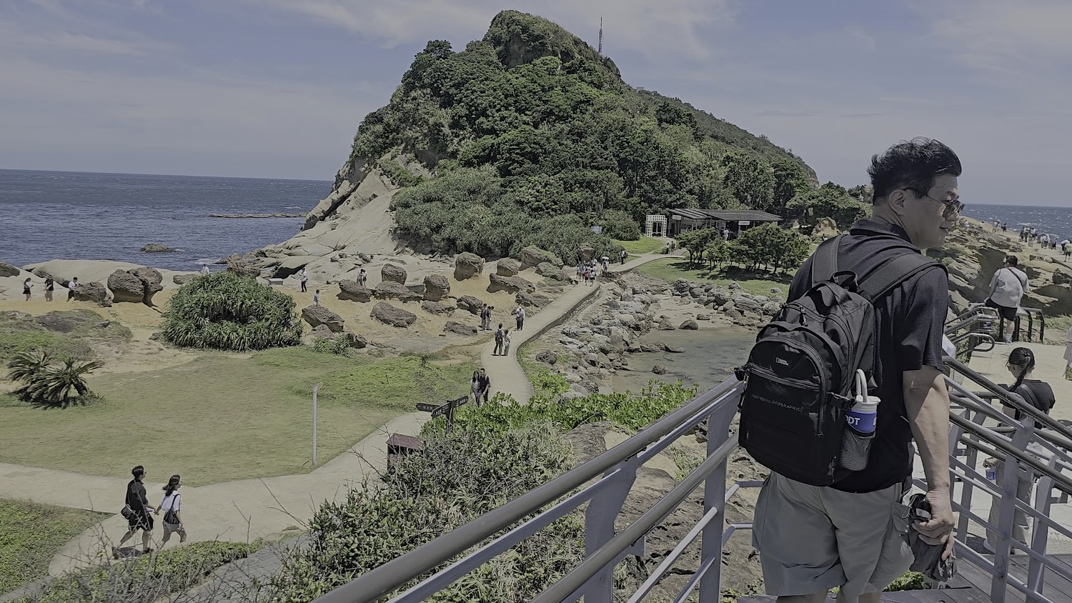 遊客站在欄杆邊遠眺海景步道與奇岩