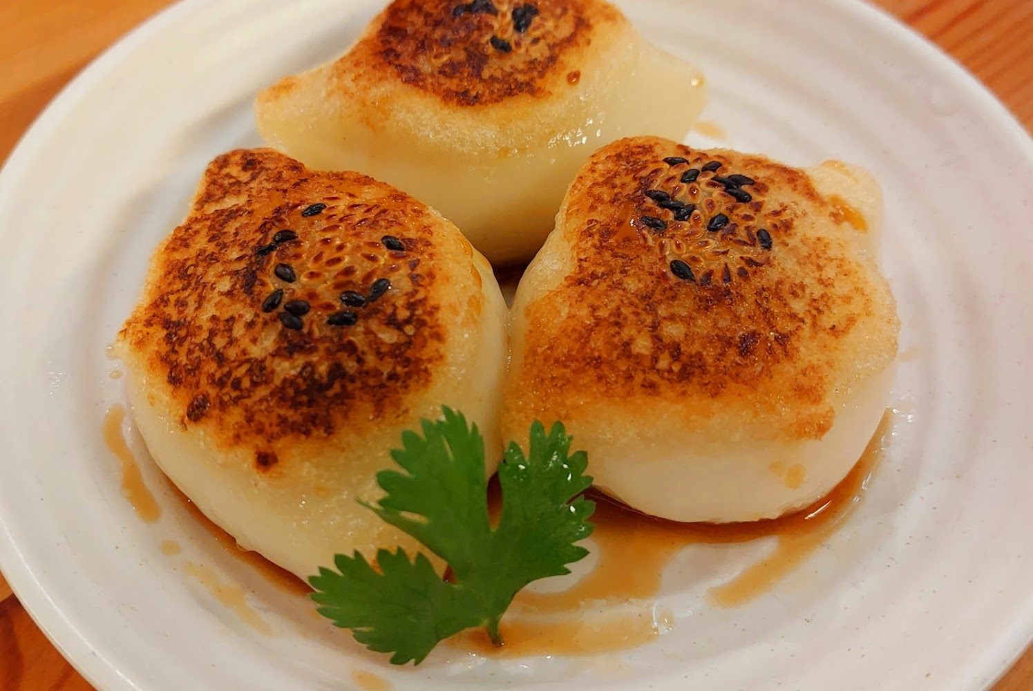 生煎包煎得金黃，灑上黑芝麻與香菜點綴