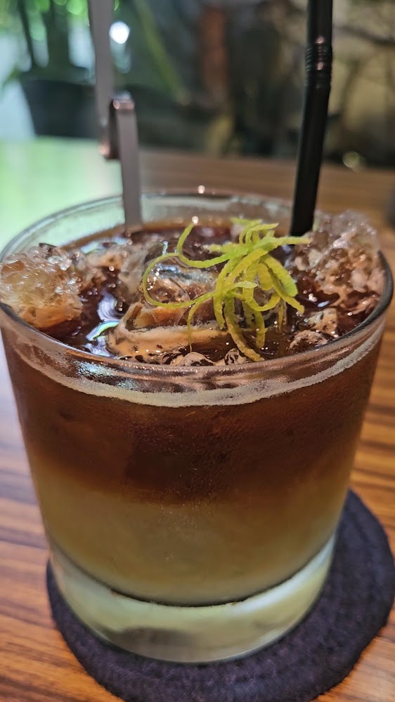 這張圖片主要是一杯加了冰塊的咖啡飲品，飲料上方有檸檬皮絲作為裝飾，放在木質桌面上，看起來清涼提神。