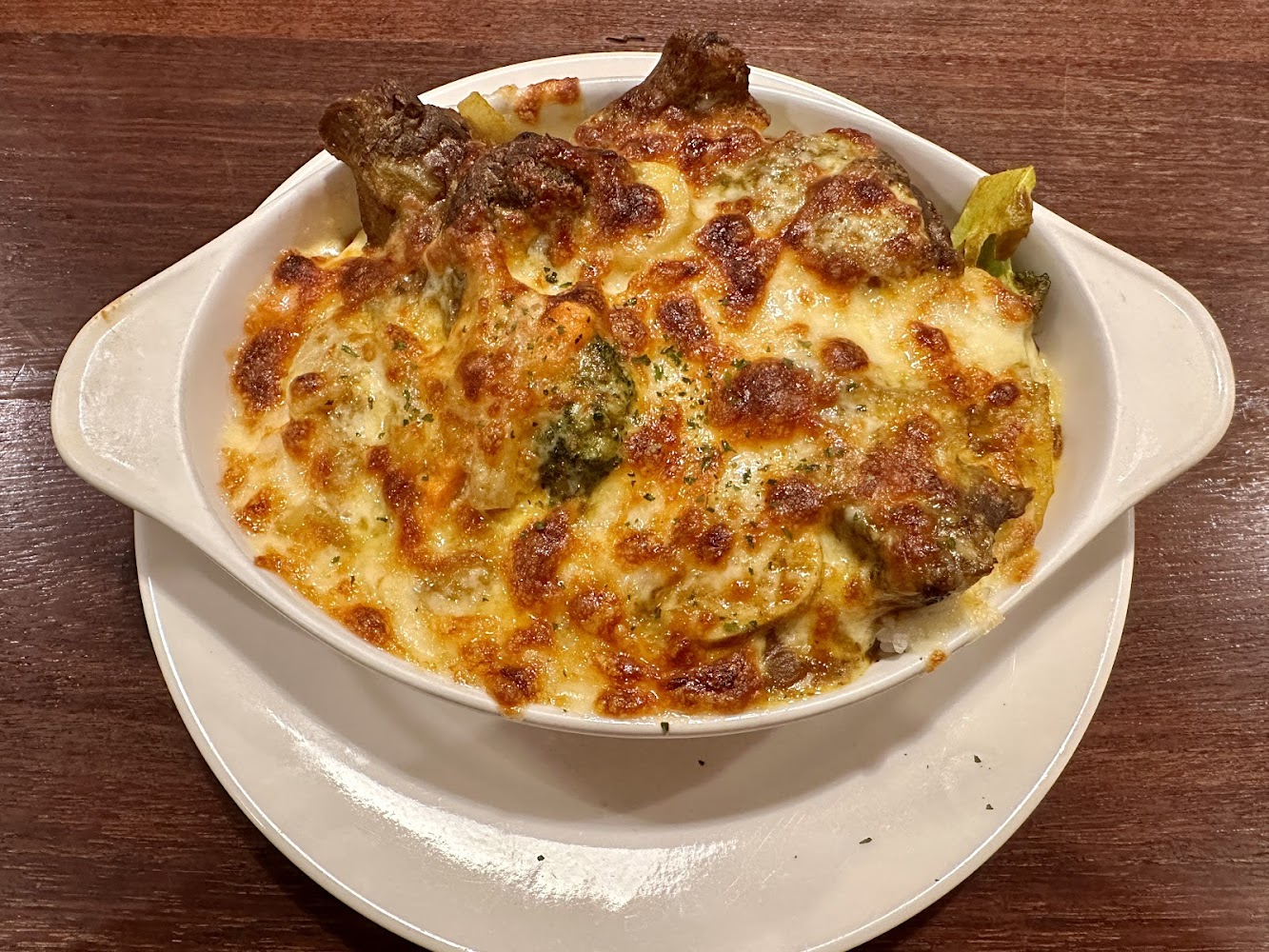 這張圖片主要是一道焗烤料理，上層鋪有金黃起司，可能包含蔬菜、肉類與米飯，整道菜色澤豐富，看起來香濃誘人。