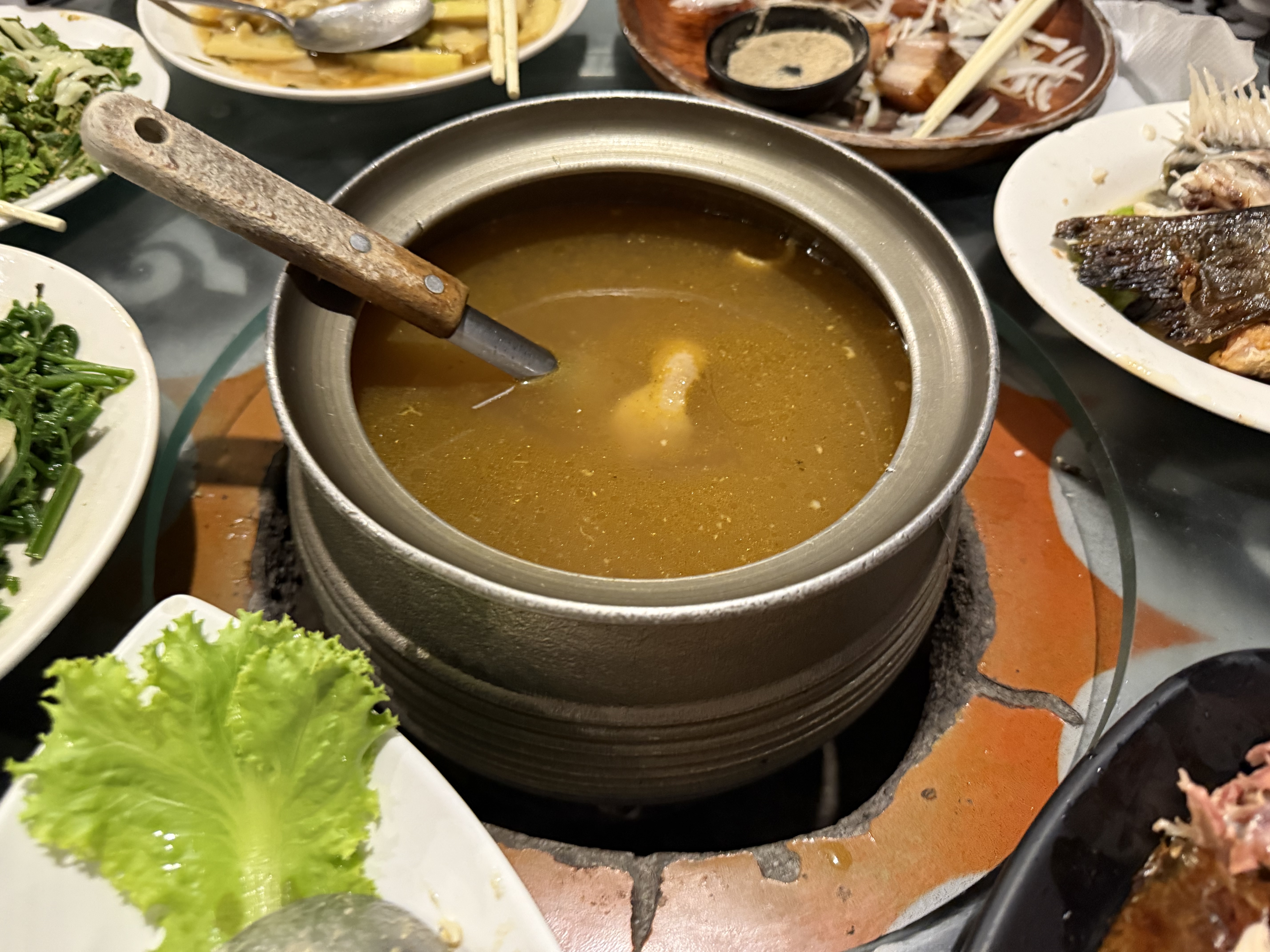 一桌豐盛的餐點，中間是熱騰騰的火鍋湯，周圍有各式蔬菜、魚肉和配菜
