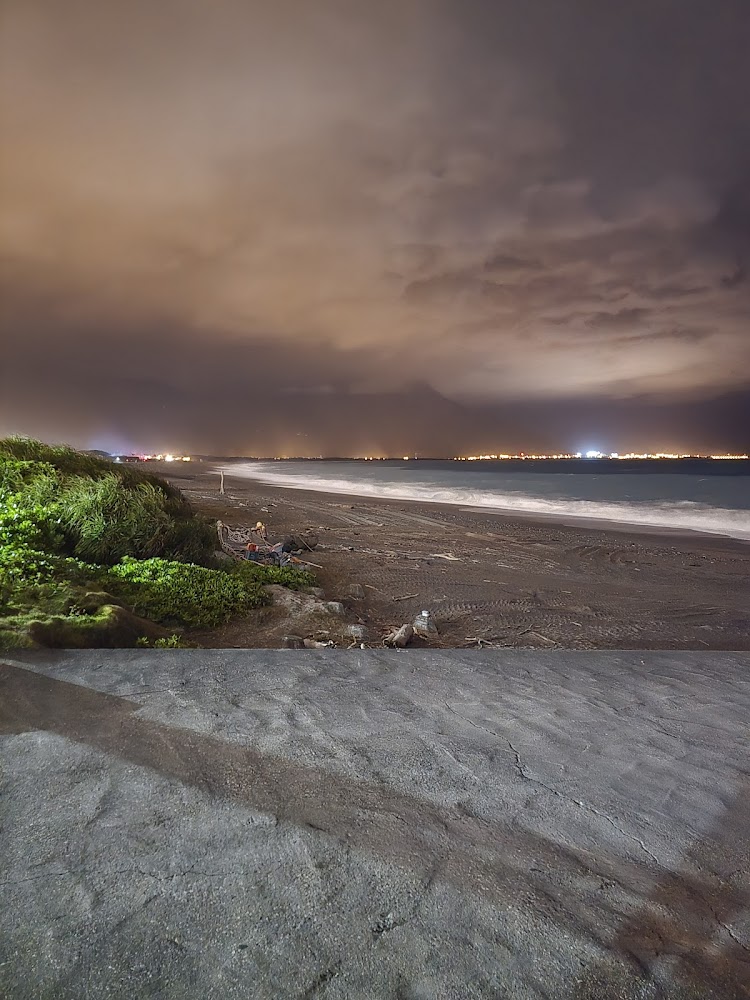 夜晚海灘雲霧天空遠方城市燈光與海浪