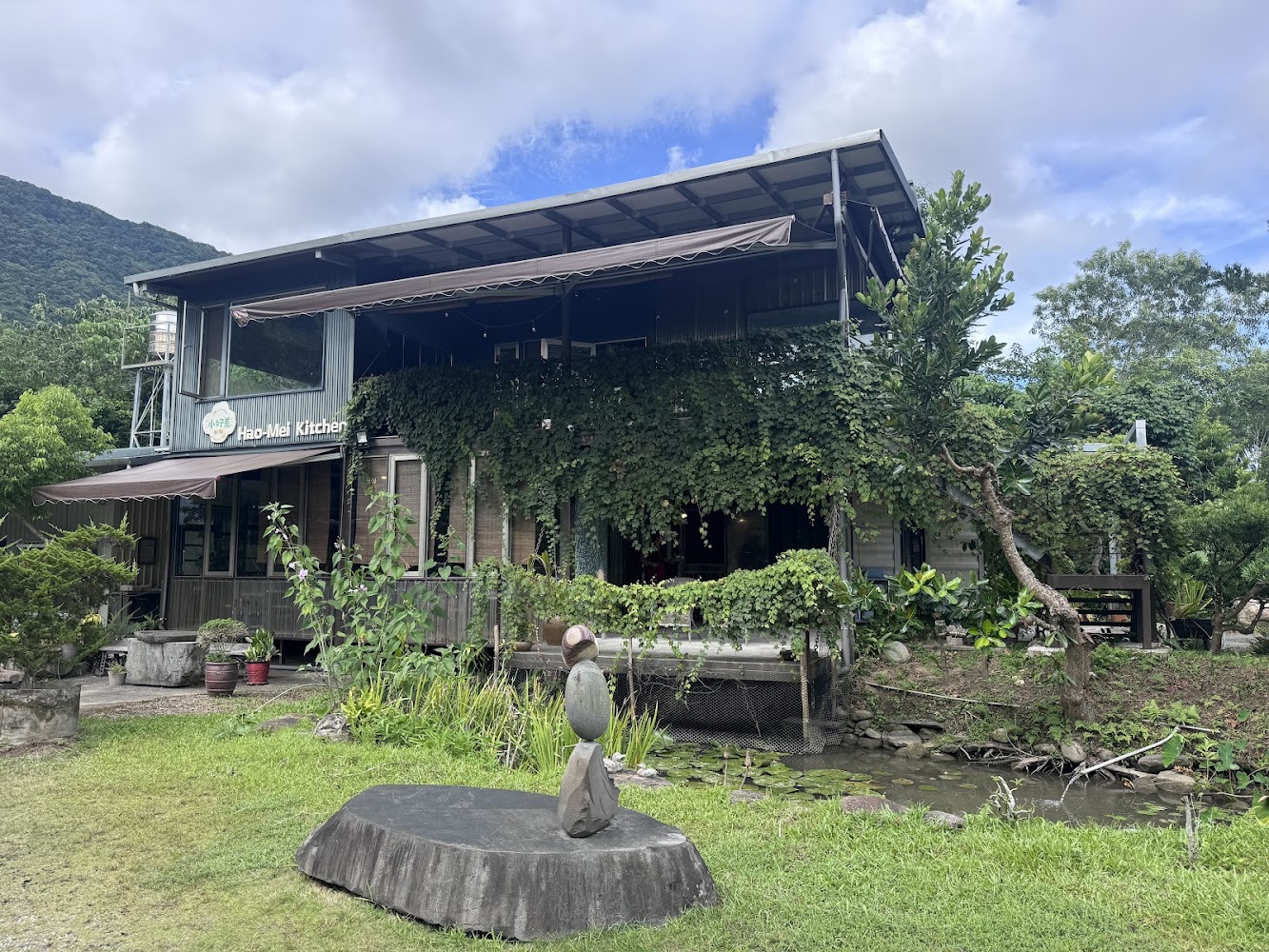 藤蔓覆蓋的小好美廚房建築與池塘景觀