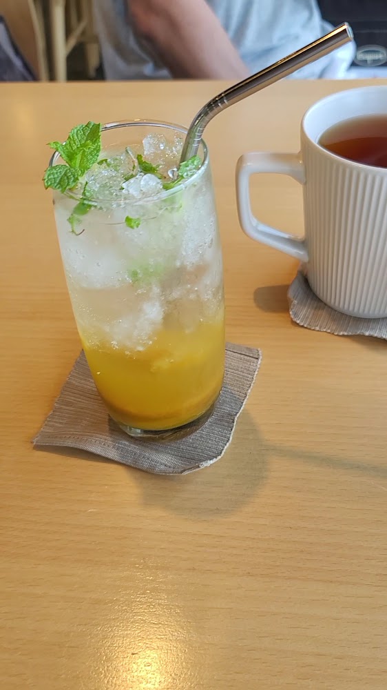 一杯加了碎冰和薄荷葉的果汁飲品，旁邊還有一杯熱茶