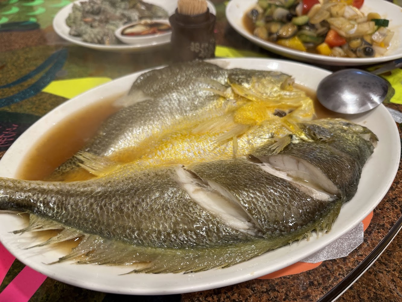 依嬤的店清蒸魚料理，旁邊有炒海鮮蔬菜與生蠔