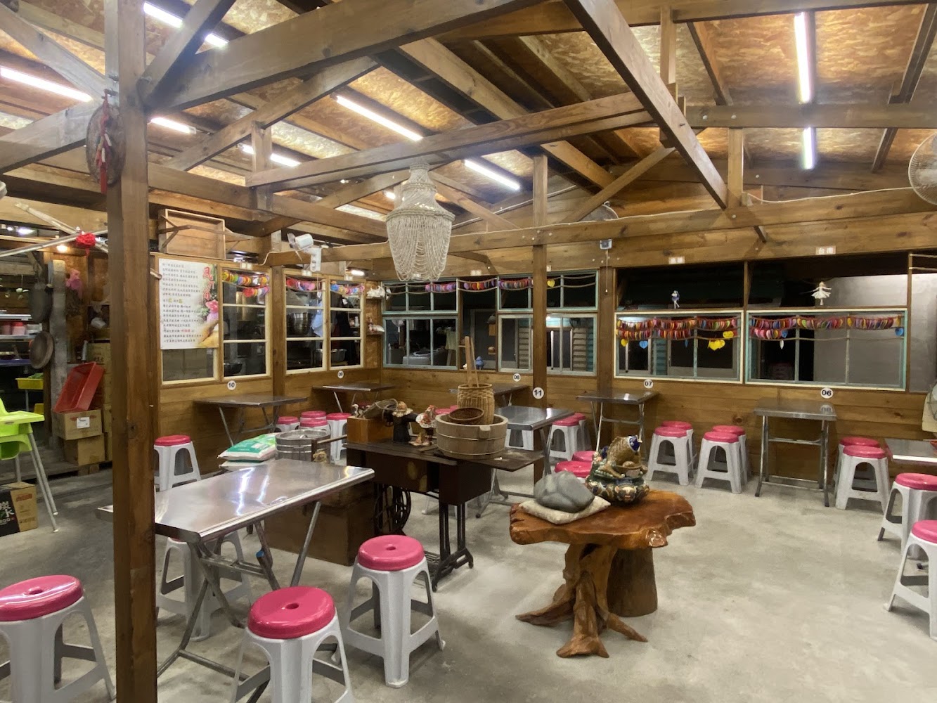 木頭裝潢餐廳內部，有金屬桌與粉紅椅墊板凳